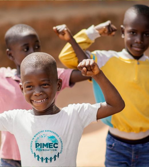Three smiling African children flexing their arms in a joyful pose, with the child in front wearing a PIMEC Foundation t-shirt, representing strength, hope, and compassion through faith-based support.
